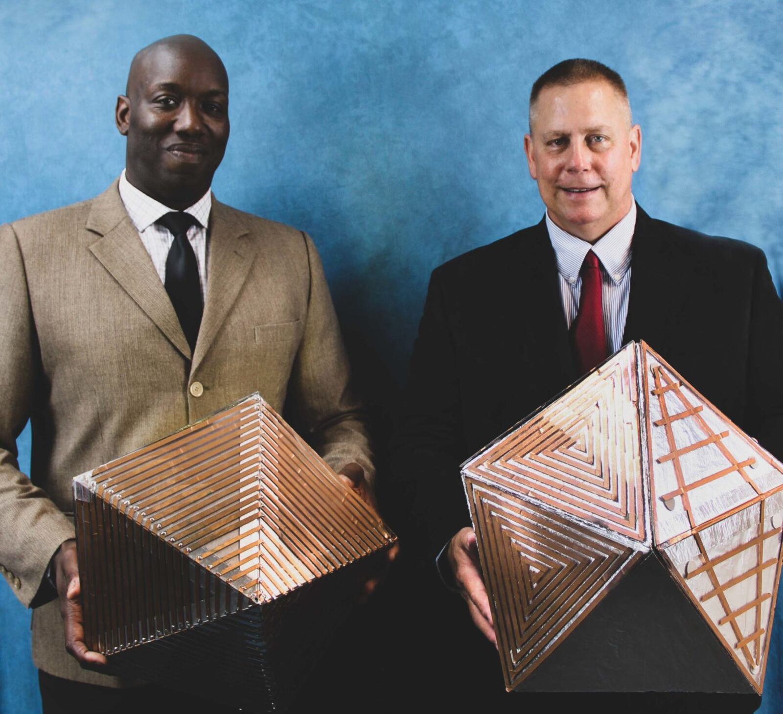 James Stewart and Gerry Miller pose for a photo with prototypes of the polygonal asymmetric reflector devices that they co-invented. (US Navy photo)