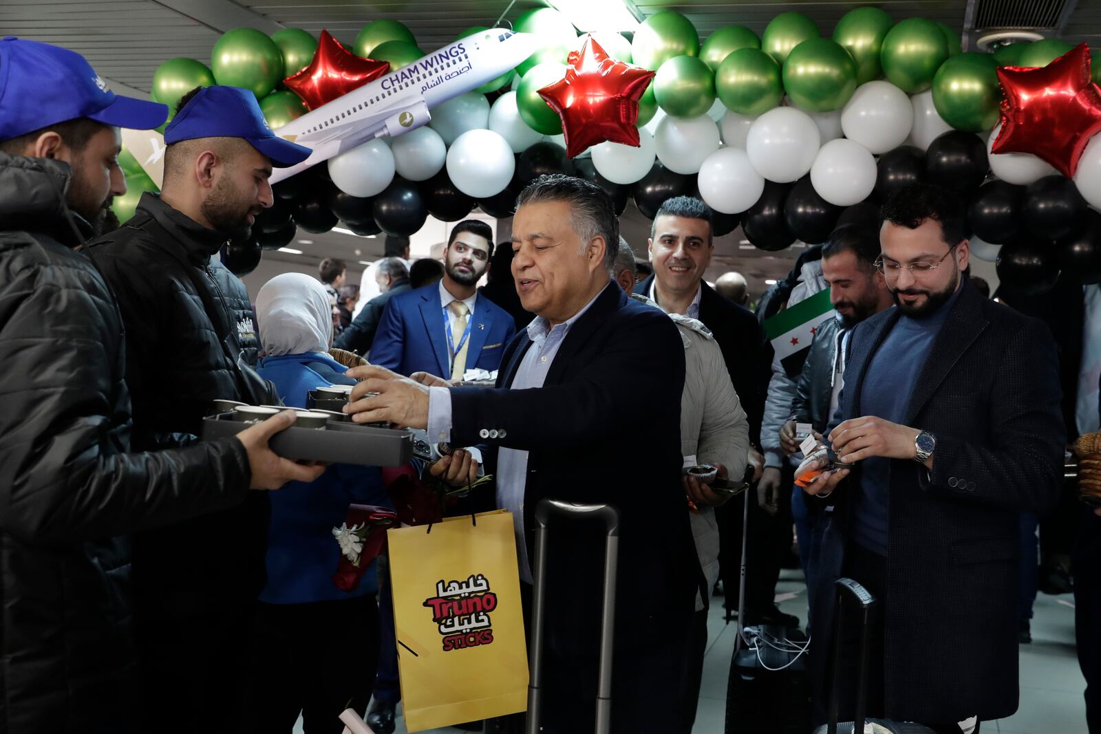 A Syrian passenger who arrived at a first international commercial flight since the fall of former Syrian President Bashar Assad, receives a coffee at the arrival terminal of Damascus international airport, in Damascus, Syria, Tuesday, Jan. 7, 2025. (AP Photo/Omar Sanadiki)