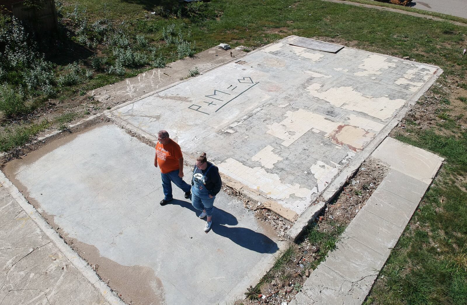 Ed Kirklin and his daughter Kenzie Banta walk over the slab foundation where their house once sat on Crosswell Avenue in Brookville. Kirklin decided to move the family to Englewood and plans not to rebuild. CHRIS STEWART / STAFF