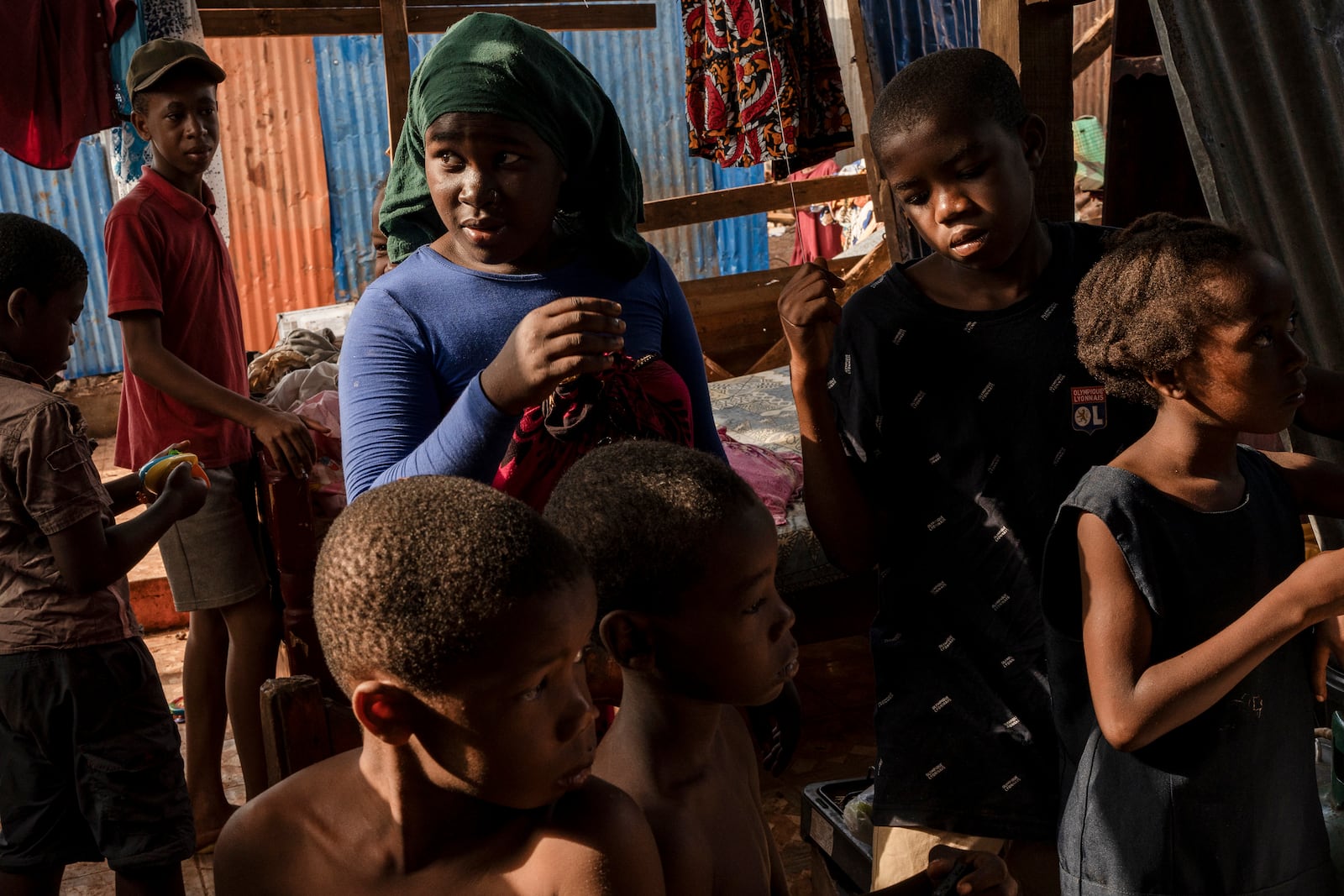 Children stand in the half destroyed house of Zaharia Youssouf in Barakani, Mayotte, Saturday, Dec. 21, 2024. (AP Photo/Adrienne Surprenant)