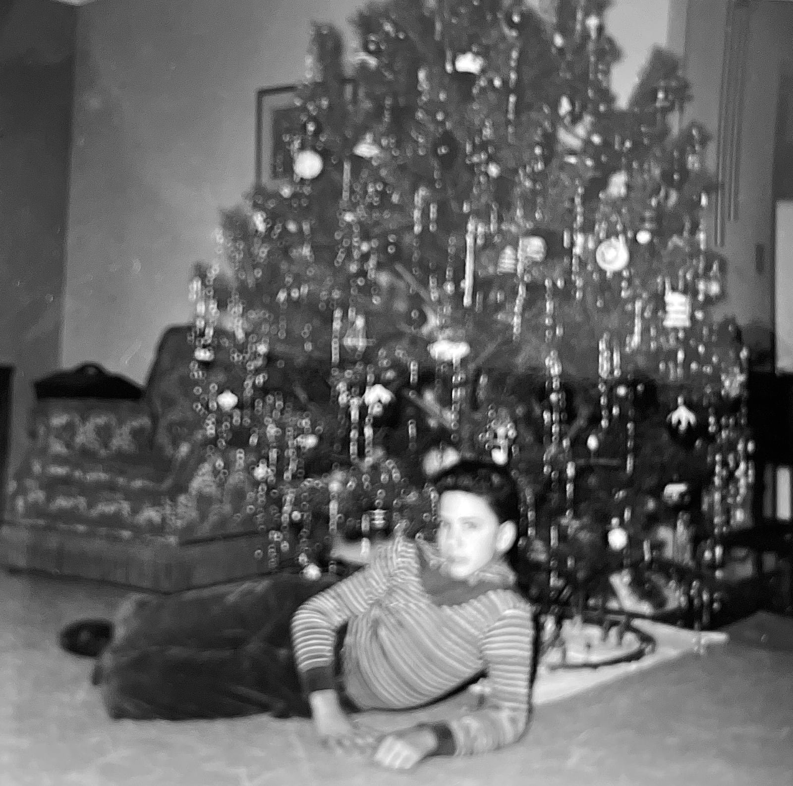 Skip Erhardt as a boy in 1957 in front of the family Christmas tree with the model train set underneath.