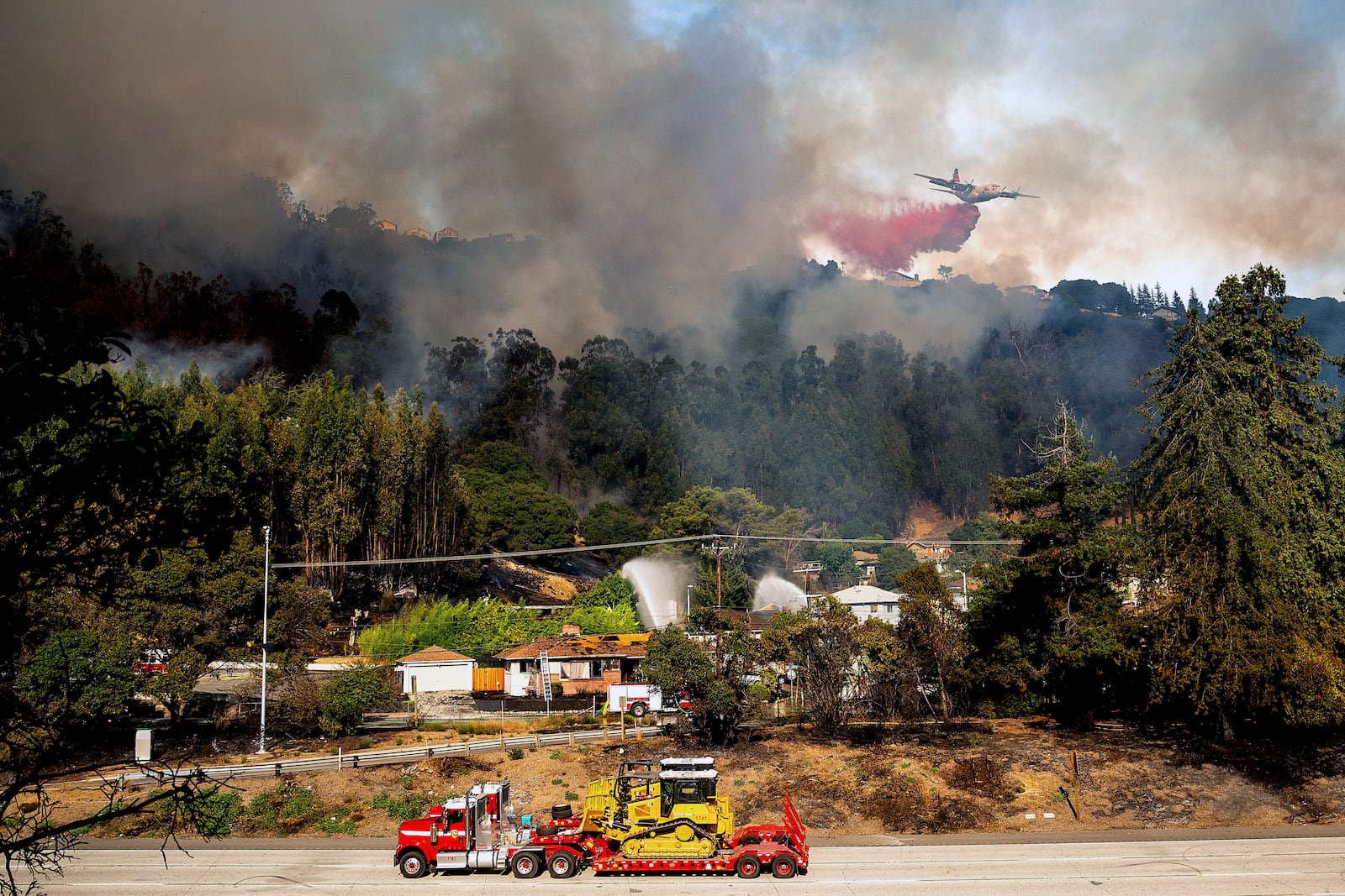 An air tanker drops retardant on a grass fire burning above Interstate 580 in Oakland, Calif., Friday, Oct. 18, 2024. (AP Photo/Noah Berger)