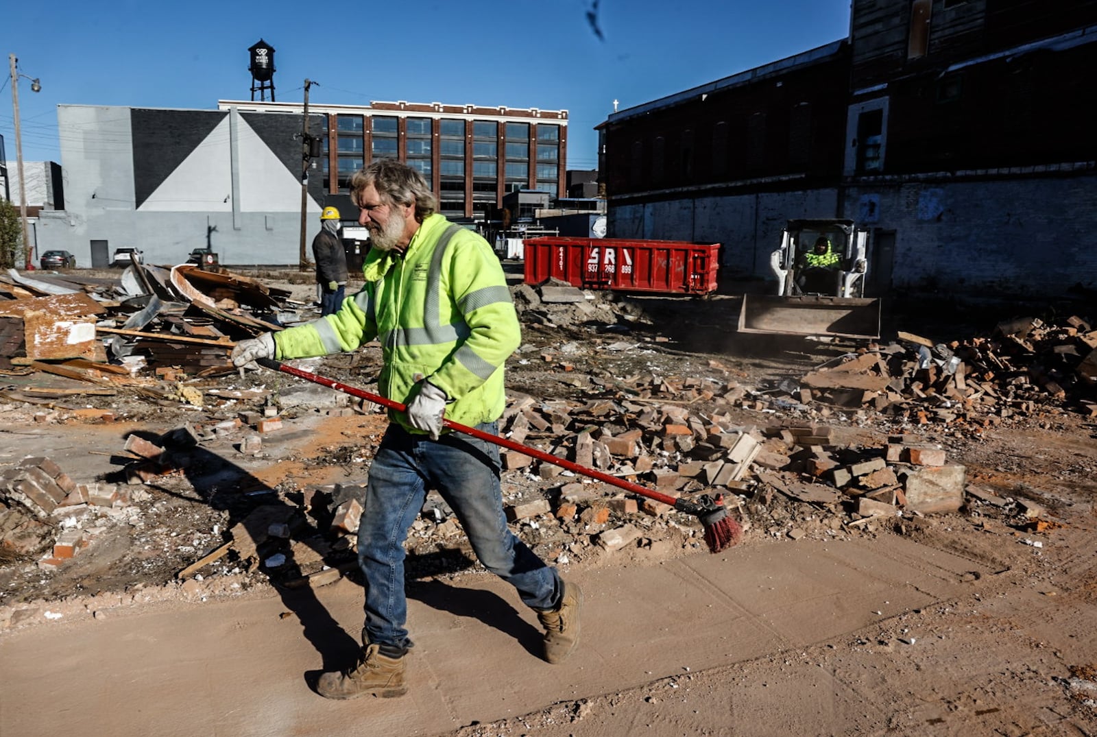 Woodard Development workers clear out a wall on East Third Street Thursday morning that collapsed due to high winds that swept through the Dayton area Wednesday night.  JIM NOELKER/STAFF