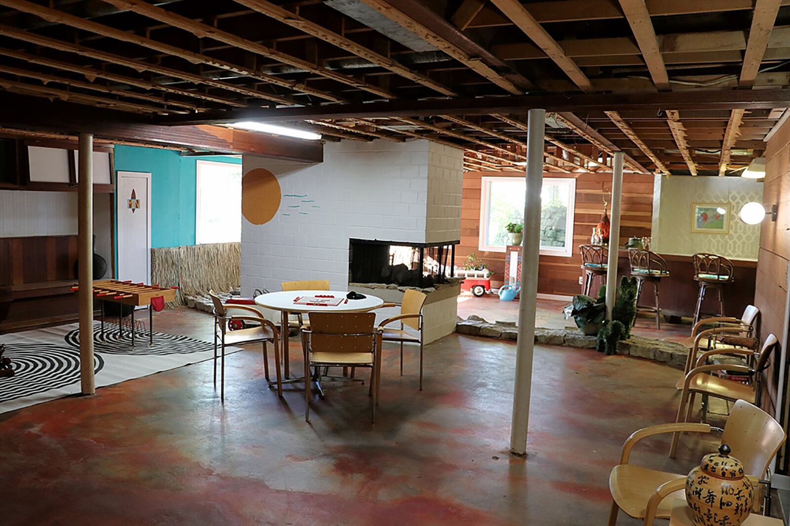 Large daylight windows fill the lower level with natural light as the space was designed into a park-like recreation and family room. Exposed ceiling joists give the space a rustic appeal and a stone walkway divides the area into two rooms. A 3-sided fireplace has a screen and can be enjoyed from the entire space. CONTRIBUTED PHOTO BY KATHY TYLER