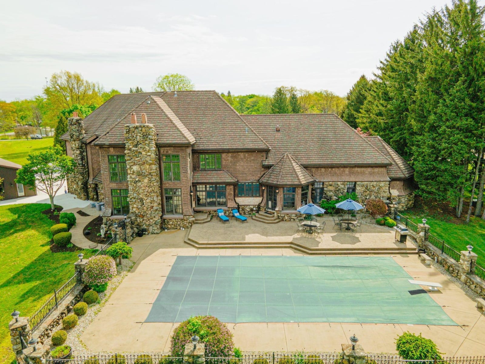 The rear of the home has an in-ground saltwater pool, a custom-stamped concrete patio, wrought-iron pool fence with stone pillars and covered patio building with a wood ceiling and fan.