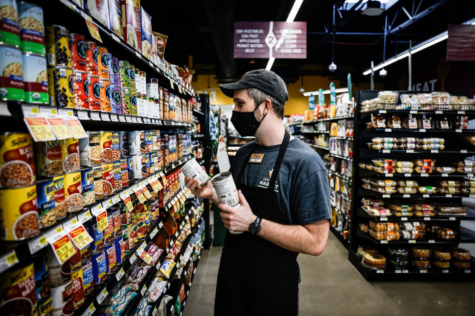 Gem City Market Deli Manager, Chris Bender, grabs cans for the lunch salad bar at the market on Tuesday May 10. 2022. This Saturday May 14, Gem City Market will hold a celebration of it's first year anniversary. JIM NOELKER/STAFF