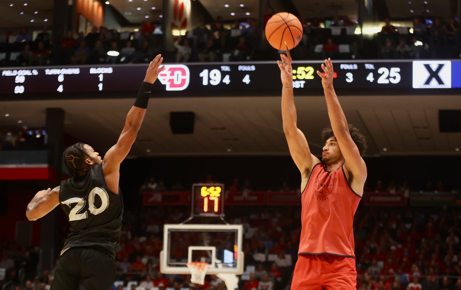 Dayton's Nate Santos makes a 3-pointer against Xavier's Dayvion McKnight in an exhibition game on Sunday, Oct. 20, 2024, at UD Arena. David Jablonski/Staff