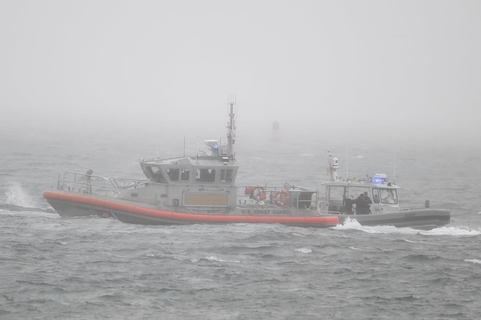 A U.S. Coast Guard boat, left, and a U.S. Navy boat work near Shelter Island after a U.S. Navy plane crashed into the San Diego Bay, Wednesday, Feb. 12, 2025, in San Diego.(AP Photo/Denis Poroy)