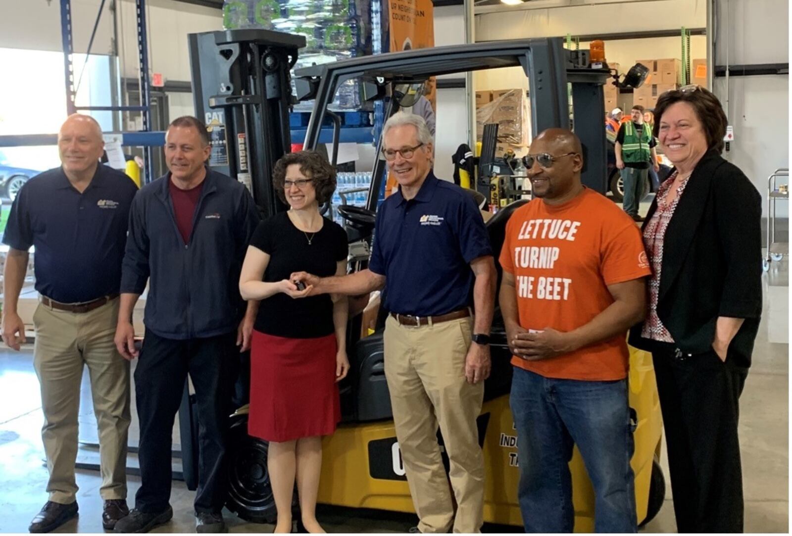 A new forklift being delivered to The Foodbank courtesy of Miami Industrial Trucks and the 100 Men Who Care organization.  
Pictured left to right are Mark Jones, Nick Green, Kate McEwen, George Malacos, chairman of the board at Miami Industrial Trucks, Anthony Stargell, and Michelle Riley, CEO of The Foodbank. CONTRIBUTED