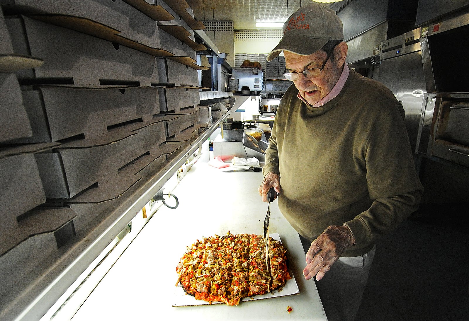 Ron Holp cuts a pizza fresh from the oven at Ron's Pizza in downtown Miamisburg Thursday, Jan. 5, 2023. The business is in the process of wrapping up remodeling that has taken more than a year. MARSHALL GORBY/STAFF