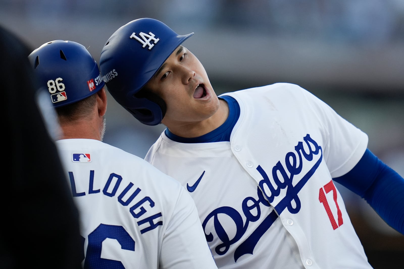 Los Angeles Dodgers' Shohei Ohtani, right, bumps heads with first base coach Clayton McCullough after his single against the New York Mets during the second inning in Game 1 of a baseball NL Championship Series, Sunday, Oct. 13, 2024, in Los Angeles. (AP Photo/Gregory Bull)