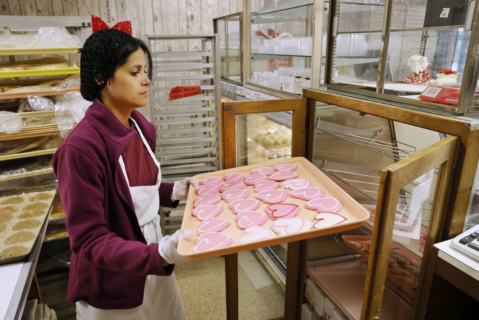 Liz Heredia refills the case with heart cookies for Valentine's Day at Central Pastry Tuesday, Feb. 14, 2023 in Middletown. NICK GRAHAM/STAFF