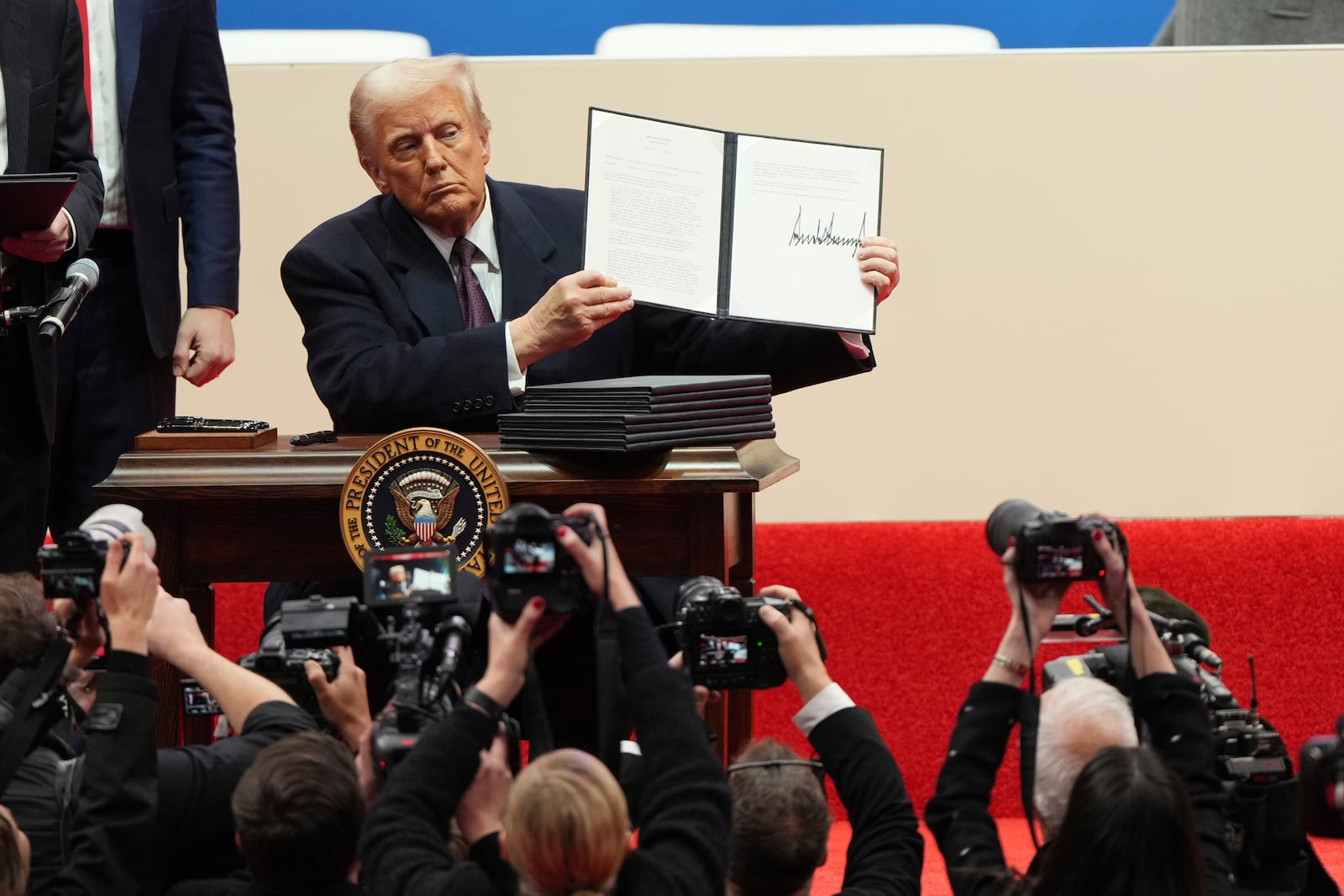 President Donald Trump holds up an executive orders after signing it at an indoor Presidential Inauguration parade event in Washington, Monday, Jan. 20, 2025. (AP Photo/Matt Rourke