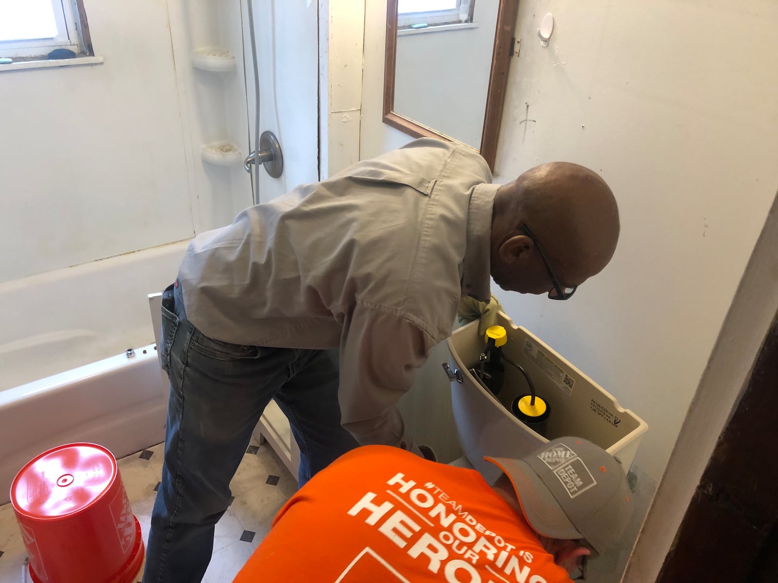 Two Home Depot volunteers, Wes Davis and David Strunk, install a toilet Monday morning in a bathroom belonging to Todd Singh, 54, a U.S. Navy veteran with disabilities. RICK McCRABB/STAFF