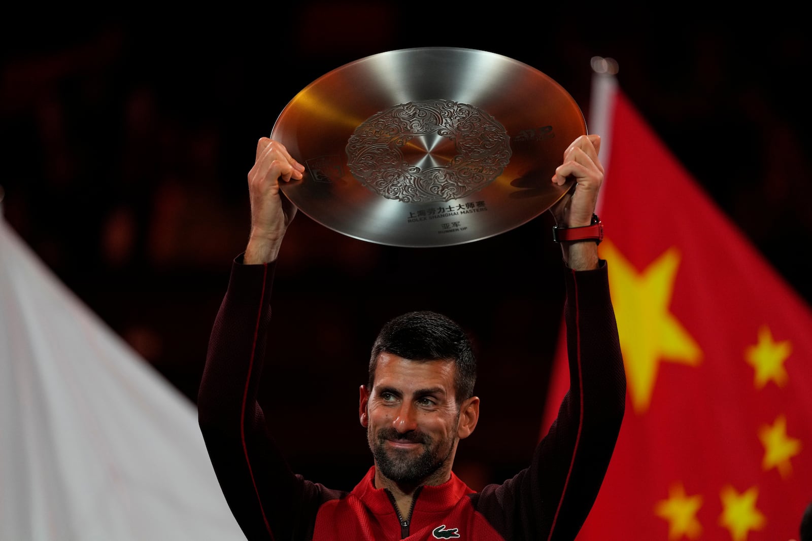 Novak Djokovic of Serbia holds ups silver medal after losing the men's singles finals match to Jannik Sinner of Italy for the Shanghai Masters tennis tournament at Qizhong Forest Sports City Tennis Center in Shanghai, China, Sunday, Oct. 13, 2024. (AP Photo/Andy Wong)