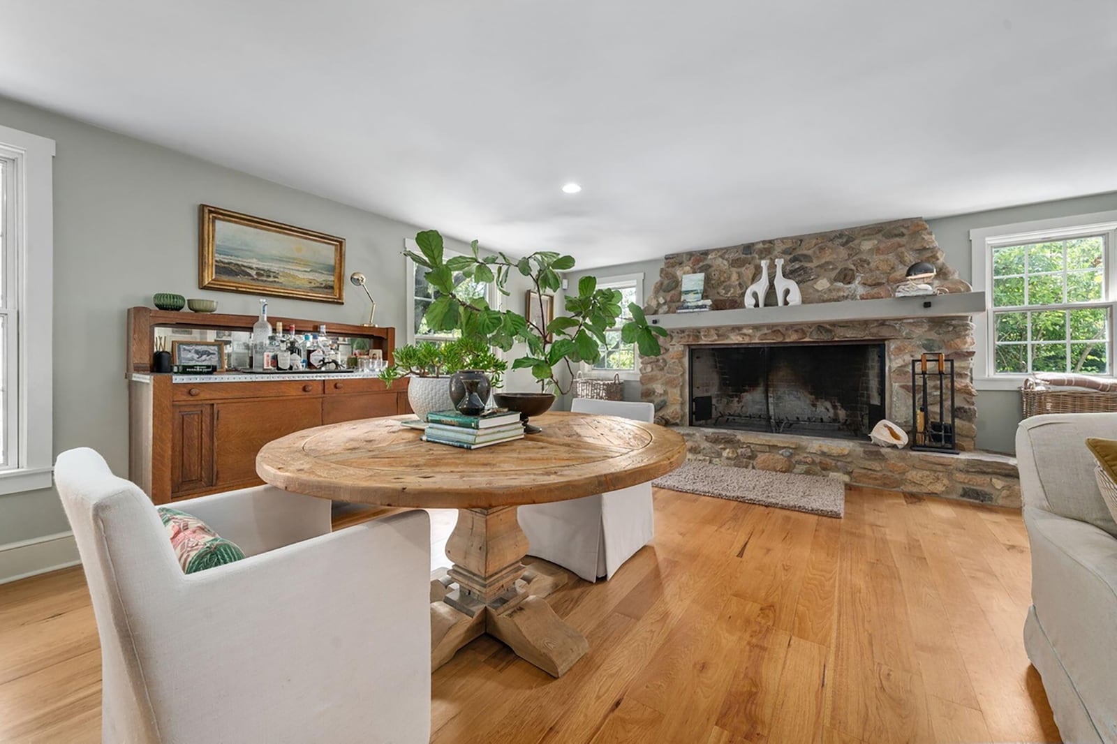 The living room has a stone woodburning fireplace and hardwood flooring.