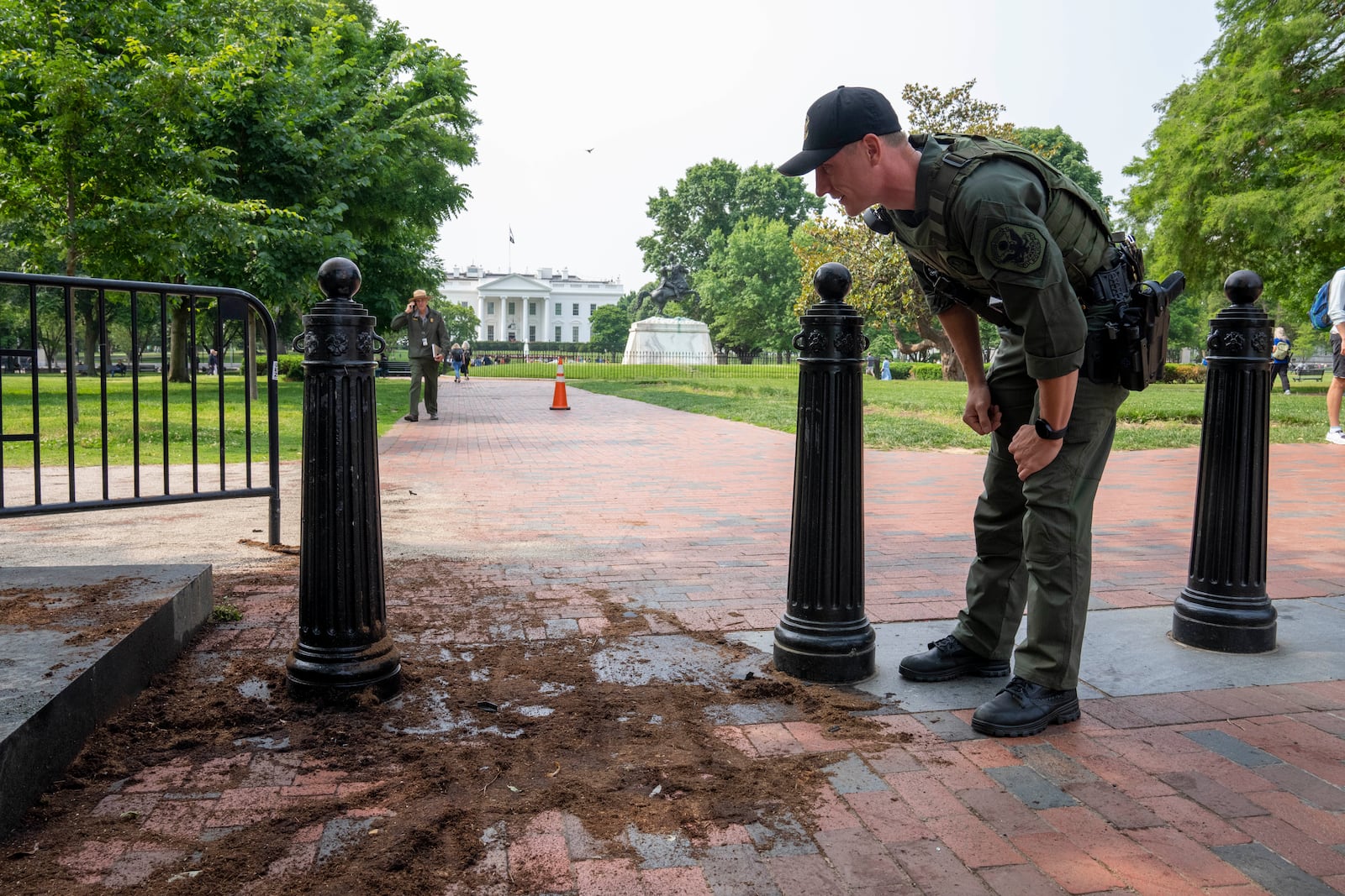 FILE - A U.S. Park Police officer inspects a security barrier for damage in Lafayette Square park near the White House, May 23, 2023, in Washington. (AP Photo/Alex Brandon, File)