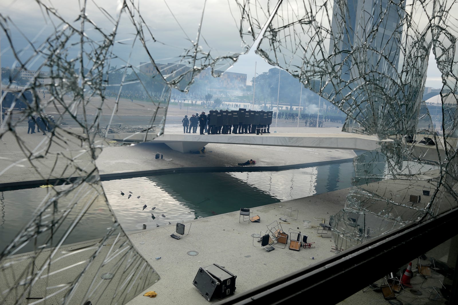 FILE - Police stand on the other side of a window at Planalto Palace that was shattered by protesters, supporters of Brazil's former President Jair Bolsonaro, after they stormed the official workplace of the president in Brasilia, Brazil, Jan. 8, 2023. (AP Photo/Eraldo Peres, File)