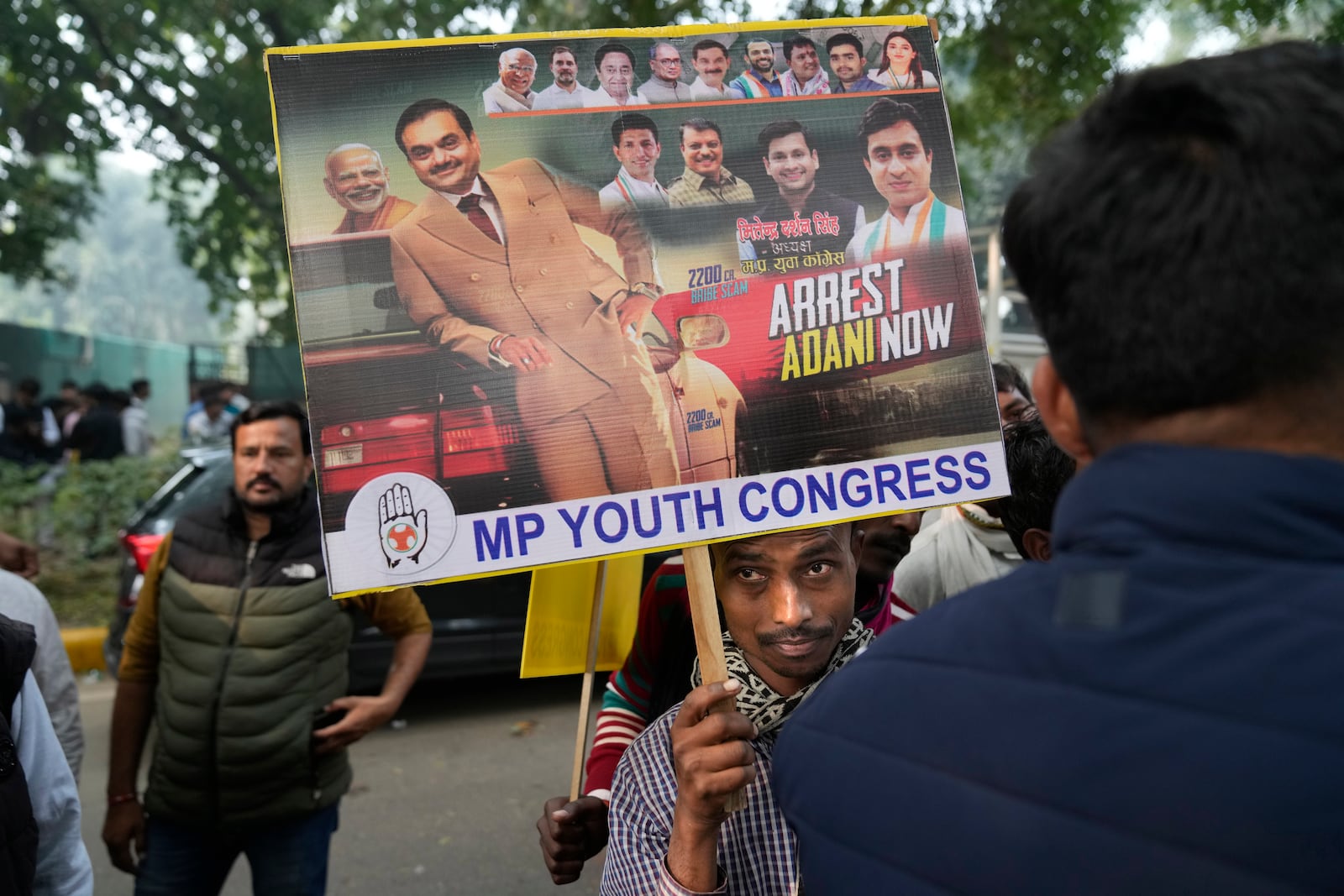 A Congress party supporter holds a banner during a protest against Indian billionaire Gautam Adani and Indian Prime Minister Narendra Modi after Adani was indicted by U.S. prosecutors for bribery and fraud, in New Delhi, India, Monday, Nov. 25, 2024. (AP Photo/Manish Swarup)