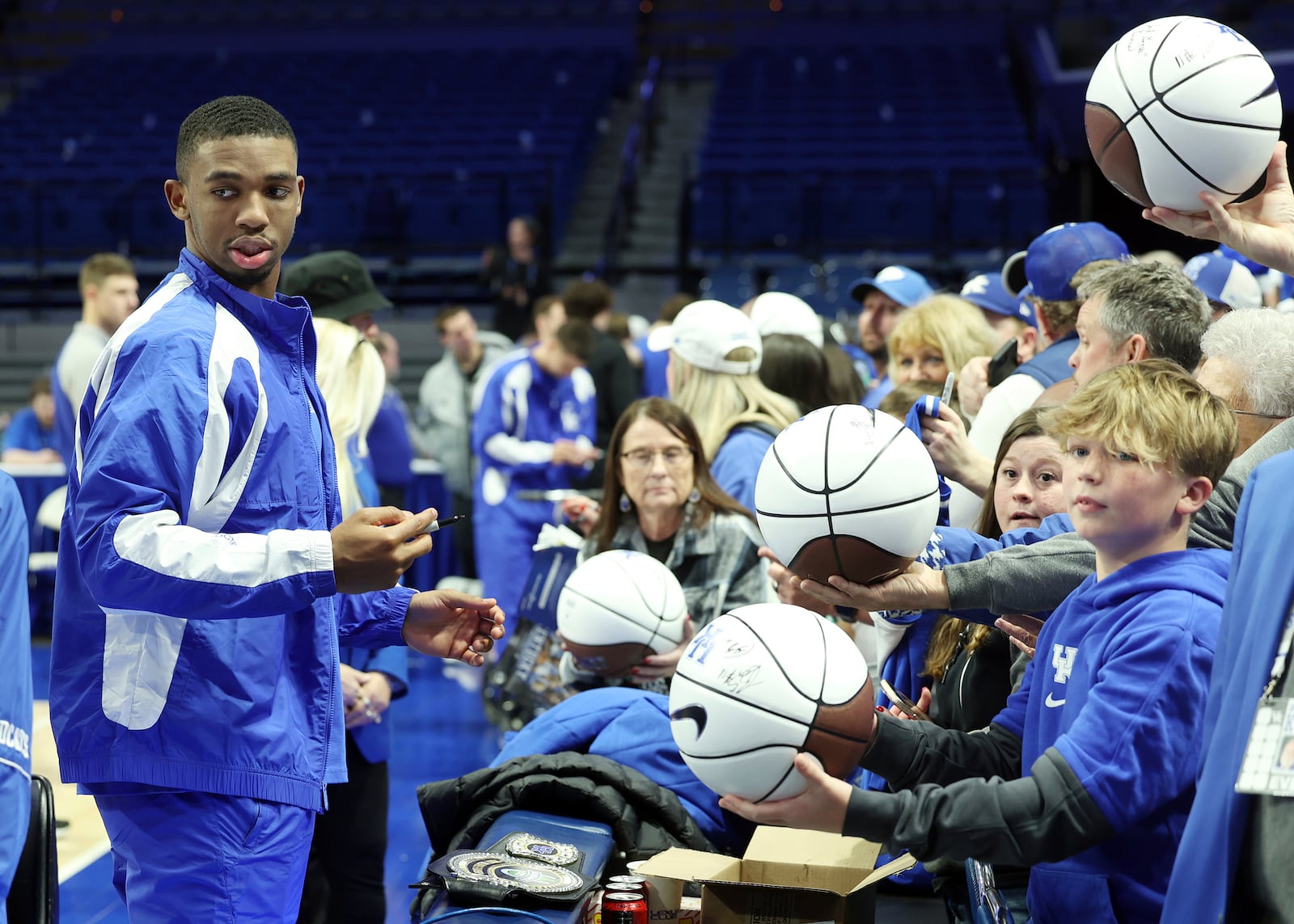 Kentucky's Lamont Butler, left, gives autographs to fans after an NCAA college basketball game against Louisville in Lexington, Ky., Saturday, Dec. 14, 2024. (AP Photo/James Crisp)