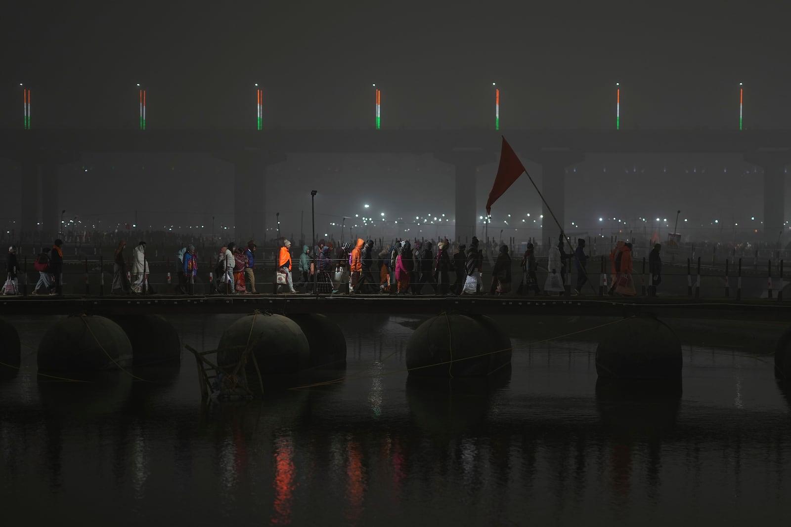 Hindu devotees cross a pontoon bridge after taking a dip at Sangam, the confluence of the Rivers Ganges, Yamuna and mythical Saraswati on one of the most auspicious day Makar Sankranti, for the Mahakumbh festival, which is one of the world's largest religious gatherings, celebrated every 12 years in Prayagraj, in the northern Indian state of Uttar Pradesh, India, Tuesday, Jan. 14, 2025. (AP Photo/Rajesh Kumar Singh)