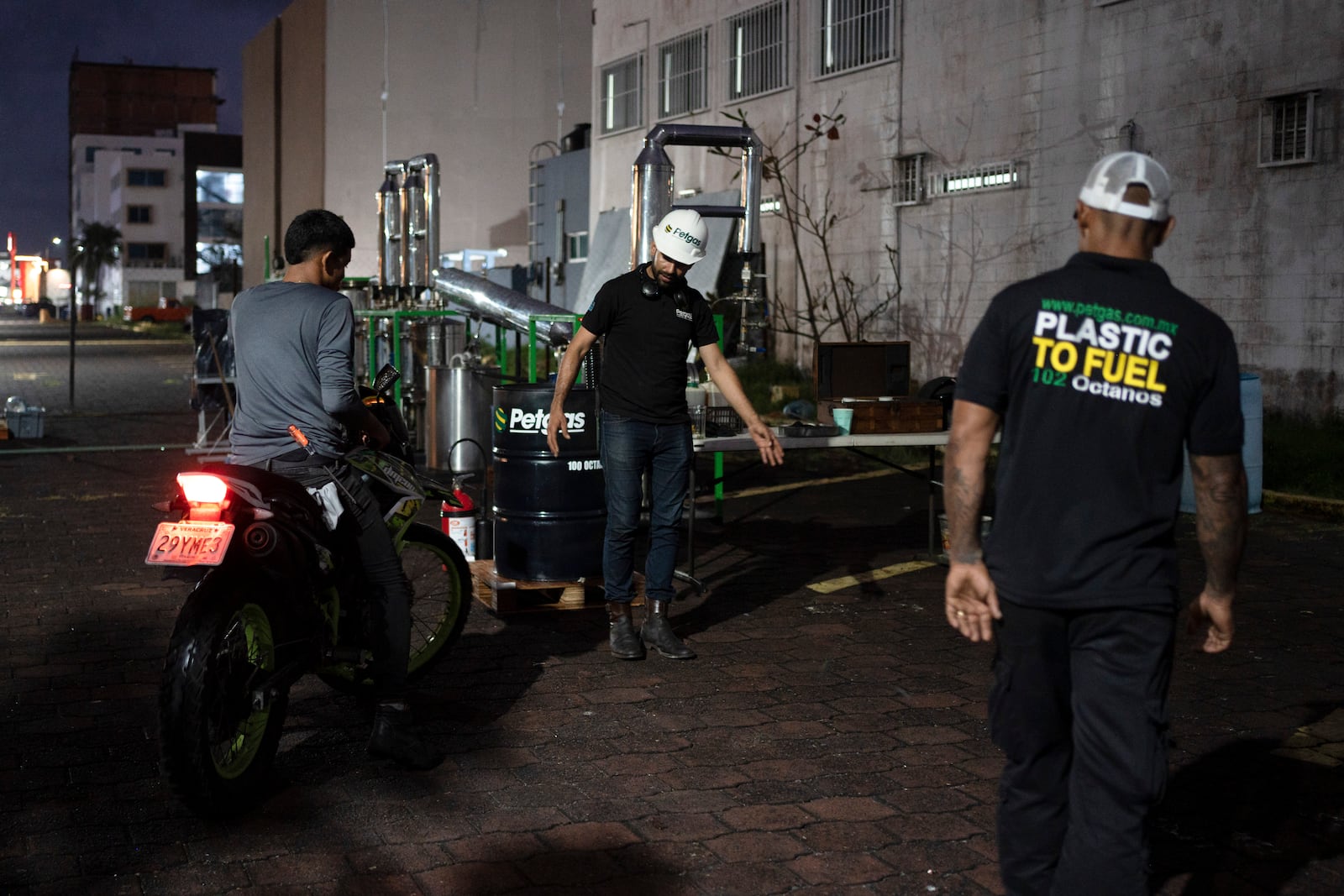 Carlos Parraguirre Diaz and Jesús Cuevas pump Petgas gasoline, made from plastic, to a motorcyclist in Boca del Rio, Veracruz, Mexico, Jan. 4, 2025. (AP Photo/Felix Marquez)