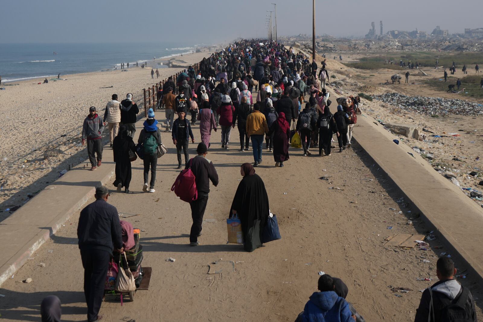 Displaced Palestinians walk on a road to return to their homes in the northern Gaza Strip, Tuesday, Jan. 28, 2025, after Israel's decision to allow thousands of them to go back for the first time since the early weeks of the 15-month war with Hamas. (AP Photo/Abdel Kareem Hana)