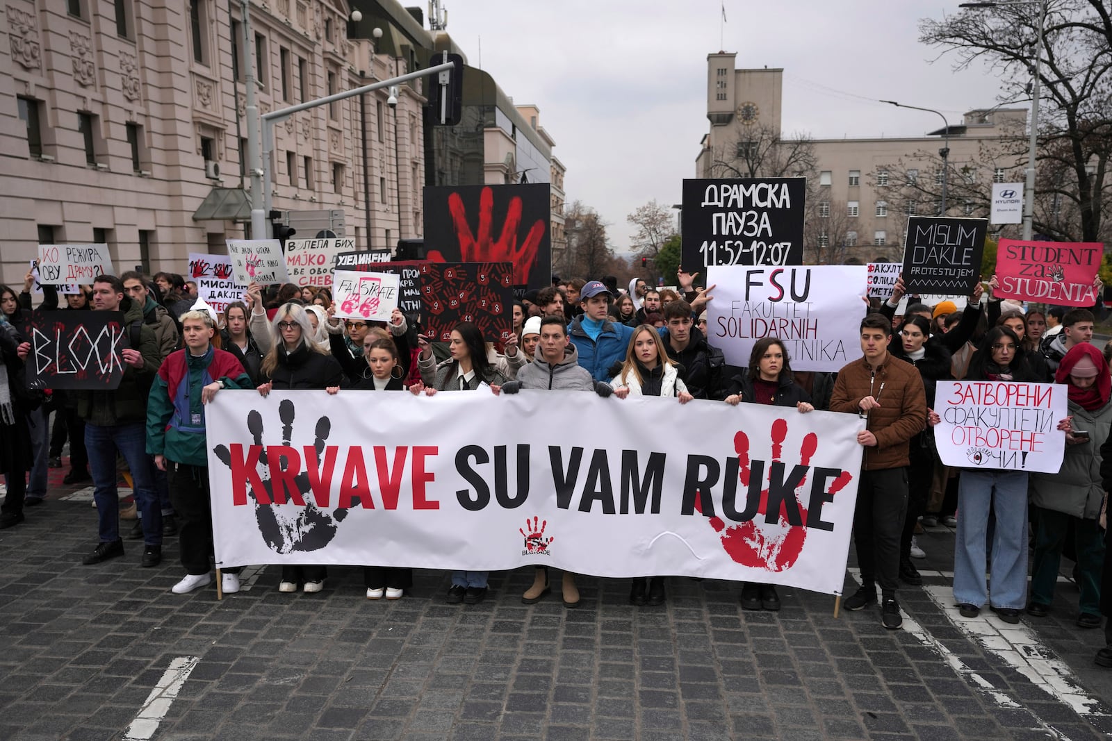 People hold a banner that reads "You have blood on your hands" and stop traffic during a silent protest to commemorate the 15 victims of a railway roof collapse six weeks ago, demand accountability for the tragedy, in Belgrade, Serbia, Friday, Dec. 13, 2024. (AP Photo/Darko Vojinovic)