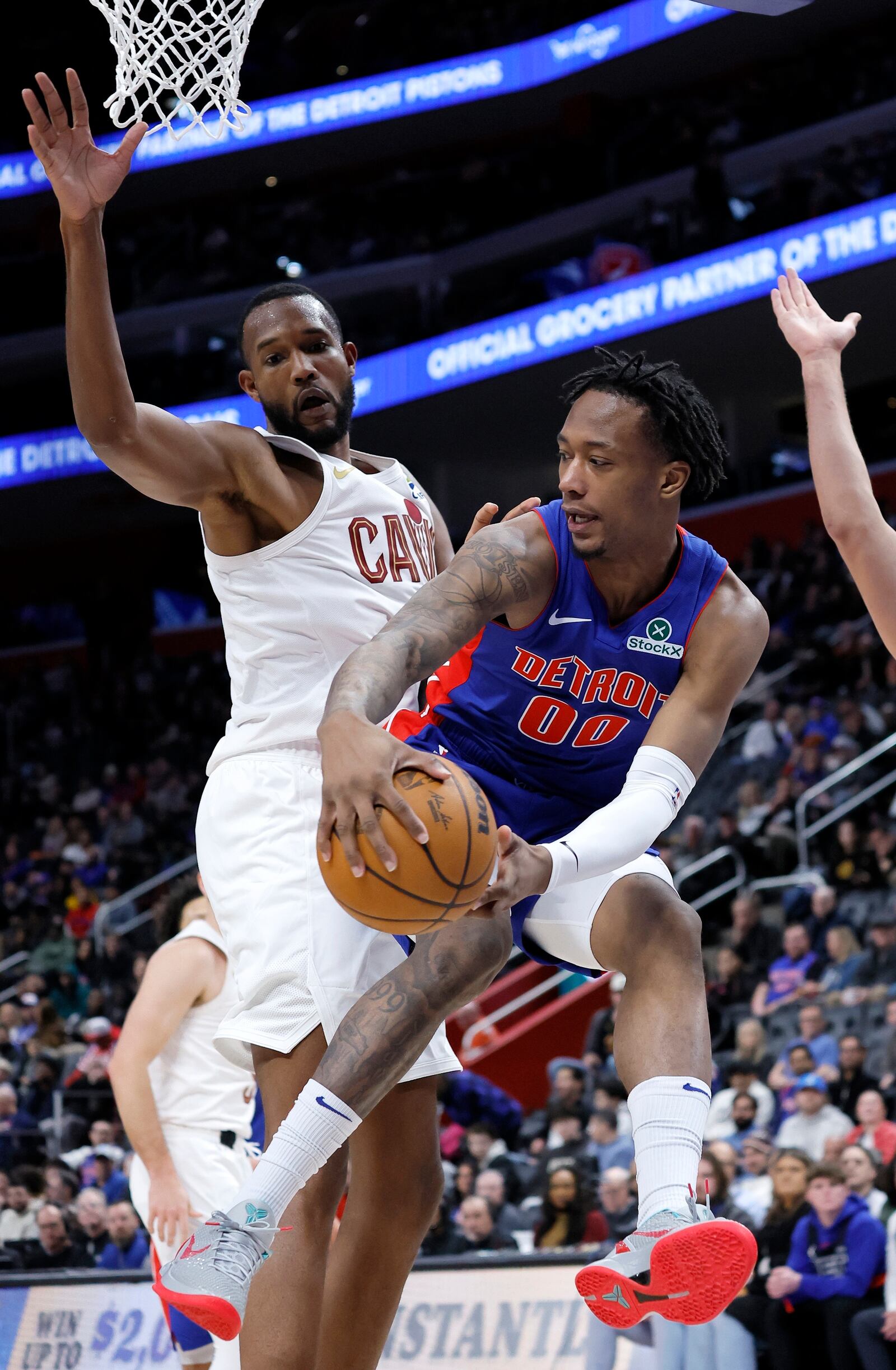 Detroit Pistons forward Ronald Holland II (00) passes the ball against Cleveland Cavaliers forward Evan Mobley, left, during the first half of an NBA basketball game Wednesday, Feb. 5, 2025, in Detroit. (AP Photo/Duane Burleson)