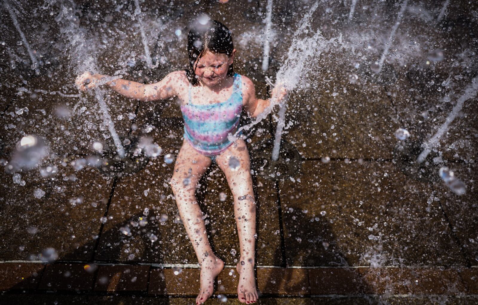 Elliana Mooney of Riverside, beats the heat Tuesday, Aug. 27, 2024, at RiverScape Metro Park fountain on Monument Street in downtown Dayton. Temperatures were in the 90s all week with several days of heat index values in the 100s before relief from the heat in time for the Labor Day holiday weekend. JIM NOELKER/STAFF