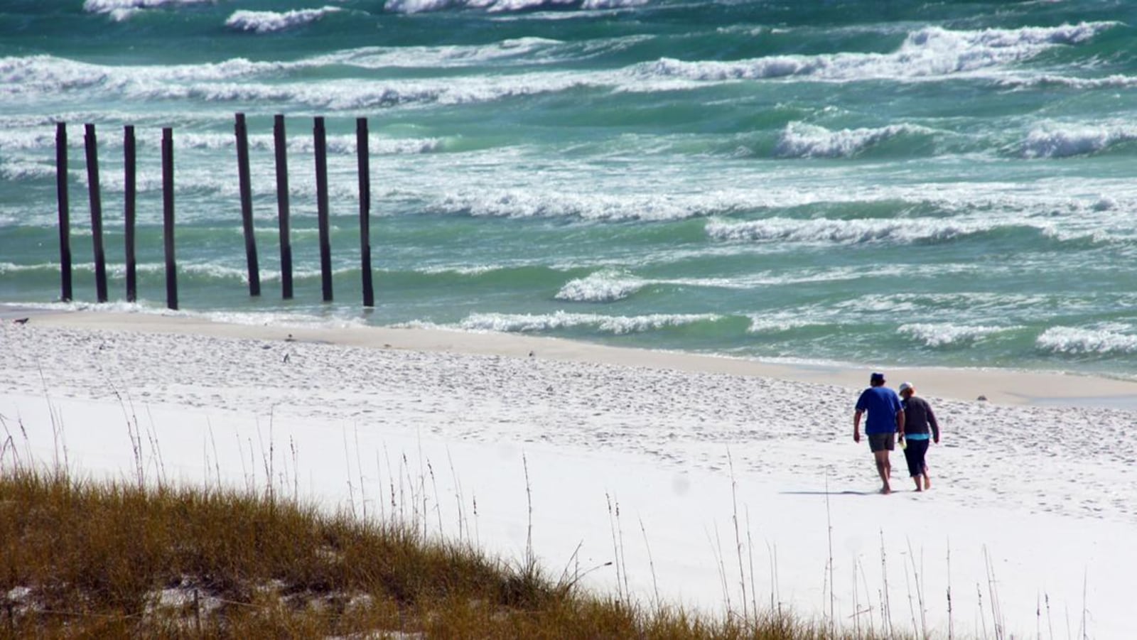 A couple walk along a beach in Destin, Florida.