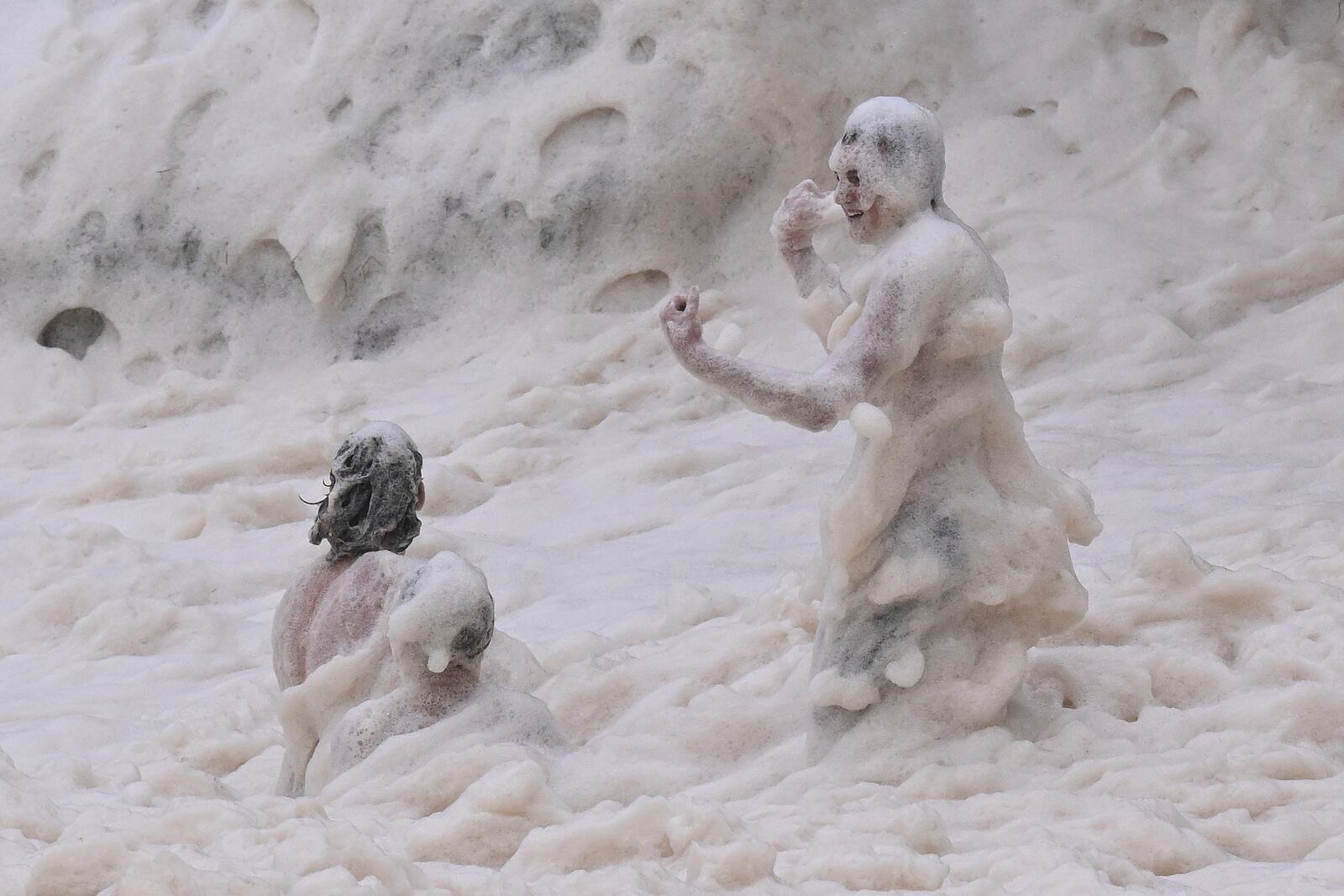 Children play in sea foam in the Coolangatta area of Gold Coast, Australia, Friday, March 7, 2025. (Dave Hunt/AAP Image via AP)