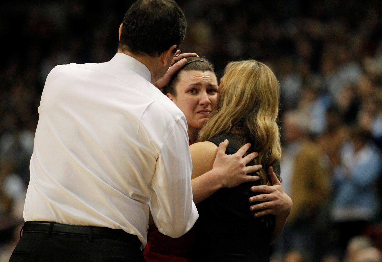 Dayton senior Andrea Hoover, center, hugs assistant coach Camryn Whitaker, right, and gets consoled by head coach Jim Jabir after leaving the court in the final minute of a loss to Connecticut on Monday, March 30, 2015, at the Times Union Center in Albany, N.Y. David Jablonski/Staff