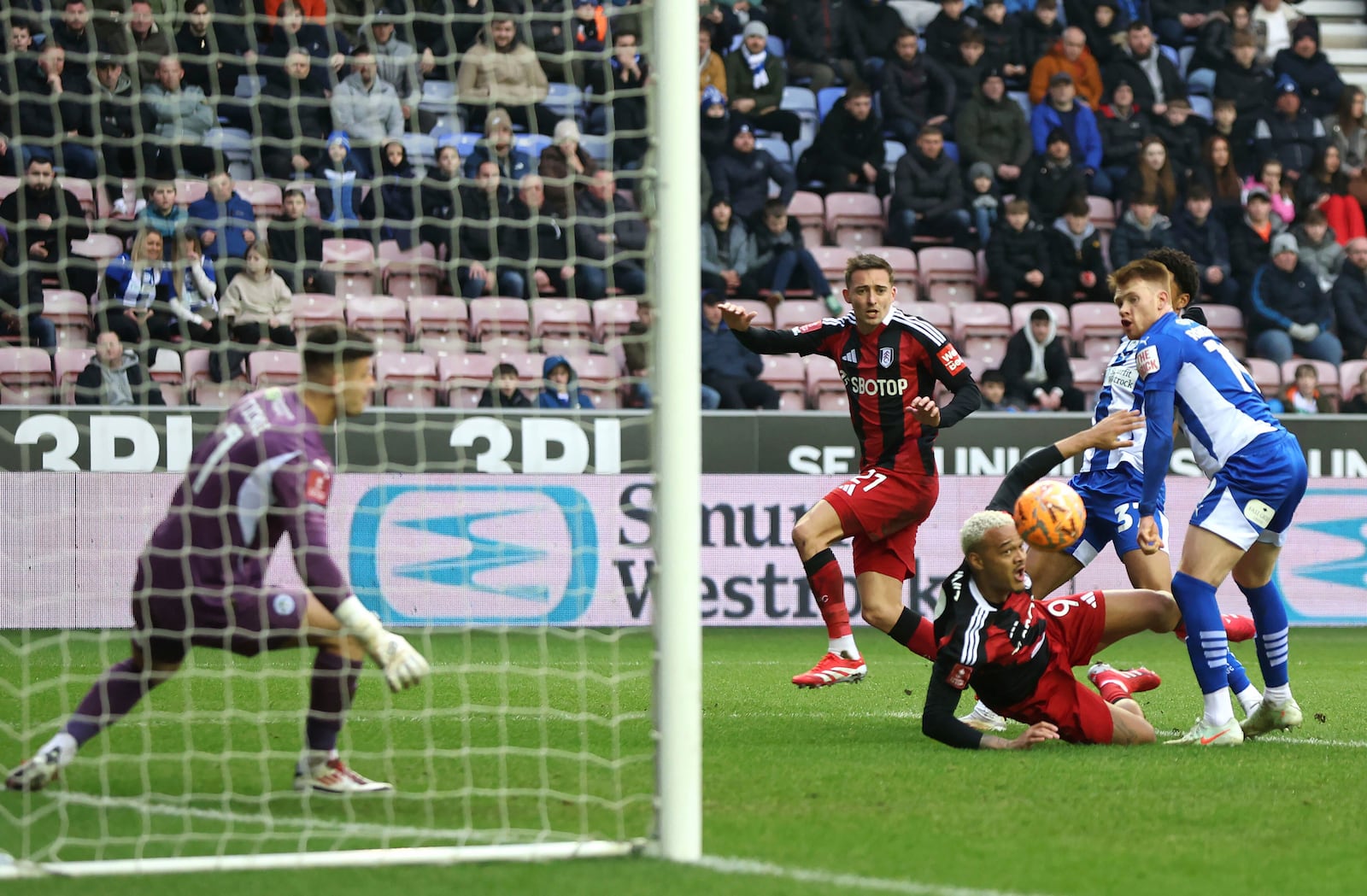 Wigan Athletic's Luke Robinson, right, scores an own goal during the Englsih FA Cup fourth round soccer match between Wigan Athletic and Fulham at The Brick Community Stadium, Wigan, England, Saturday Feb. 8, 2025. (Barrington Coombs/PA via AP)