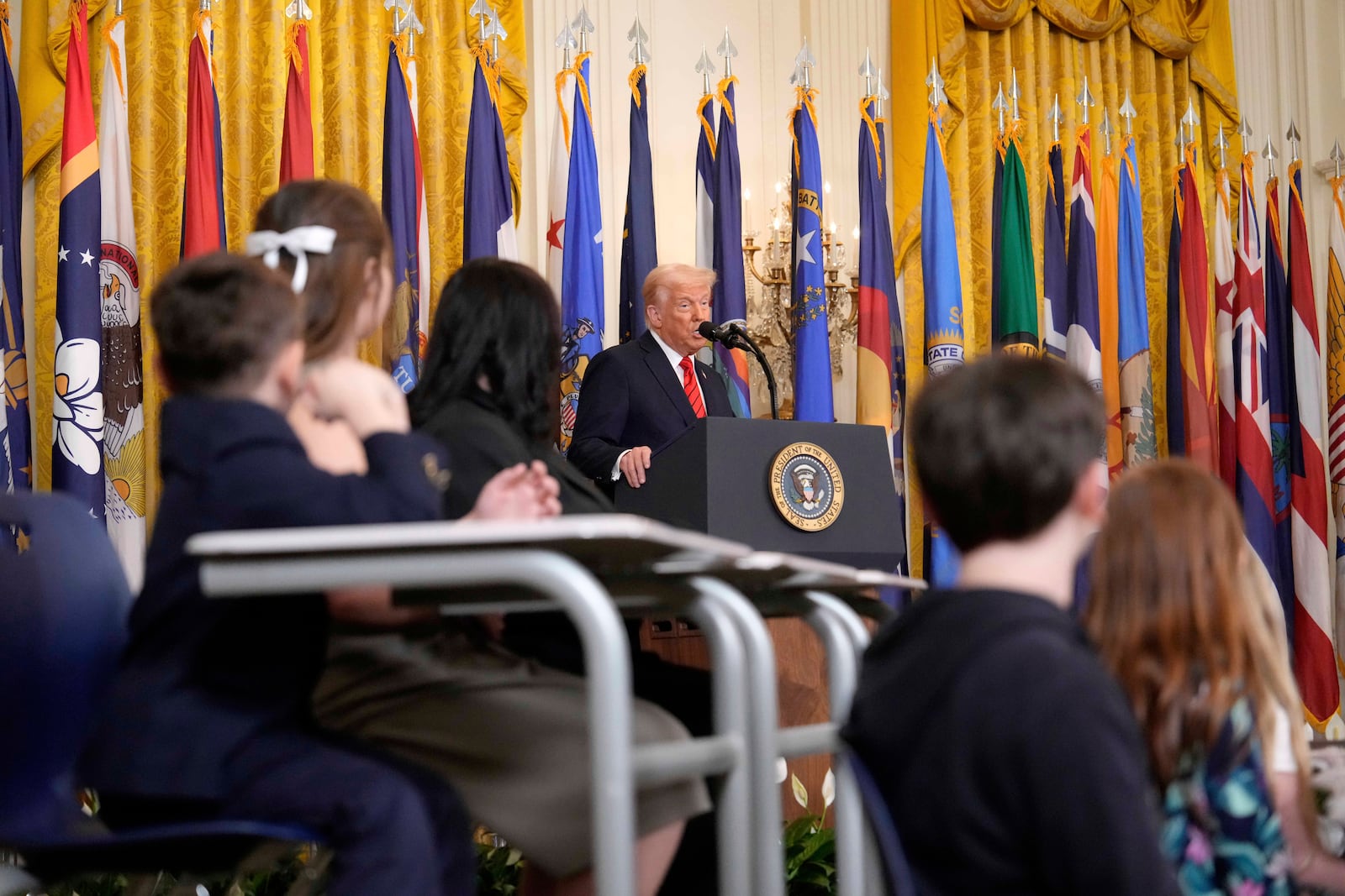 Young people listen as President Donald Trump speaks at an education event and executive order signing in the East Room of the White House in Washington, Thursday, March 20, 2025. (AP Photo/Ben Curtis)