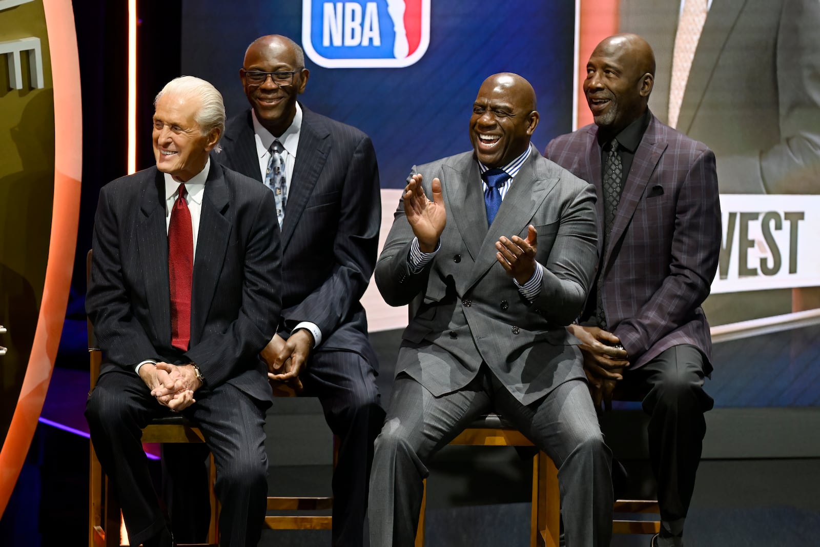 Magic Johnson, second from right reacts as Jonnie West speaks during his father Jerry West's enshrinement in the Basketball Hall of Fame, as he sits with from left, Pat Riley, Bob McAdoo and James Worthy, Sunday Oct. 13, 2024, in Springfield, Mass. (AP Photo/Jessica Hill)