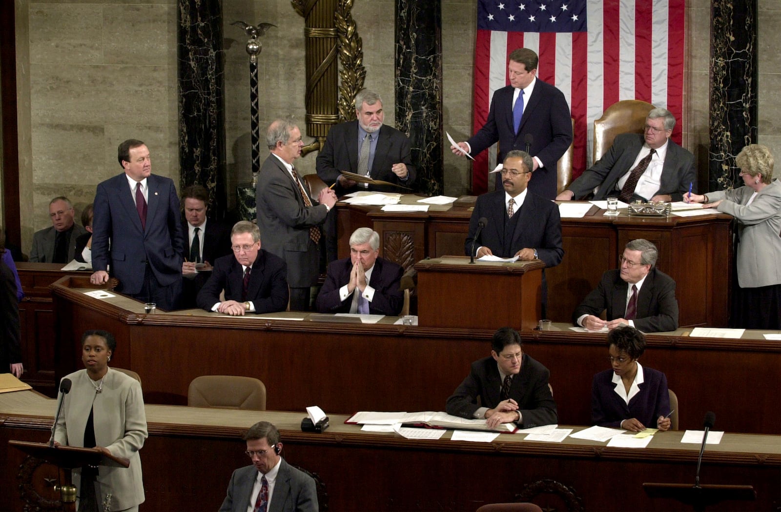 FILE - Rep. Cynthia McKinney, D-Ga., lower left, objects to Florida's electoral vote count results, as Vice President Al Gore, standing, top center, and House Speaker Dennis Hastert, R-Ill., seated, top right, listen on the floor of the U.S. House of Representatives, in Washington, Jan. 6, 2001. Other members present, seated at left in middle row are: Sen. Mitch McConnell, R-Ky., Chris Dodd, D-Ct, hand over mouth., Chaka Fattah, D-Pa., standing at podium and Rep. William Thomas, R-Calif. Others not identified. (AP Photo/Kenneth Lambert, File)