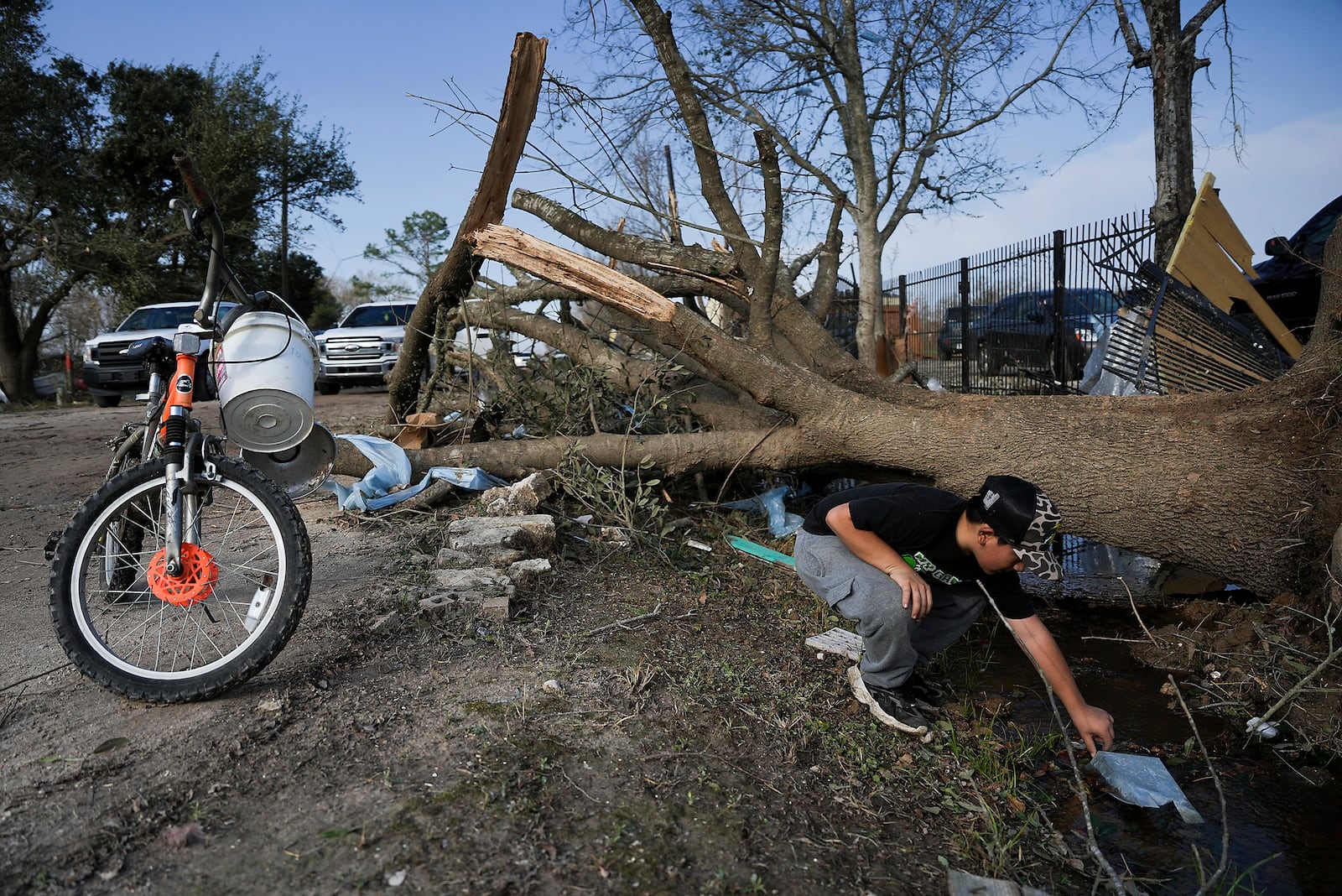 J.C. Betanzos, 11, looks for items from his sister's business and things his deceased mother gave them that blew away during a tornado, Saturday, Dec. 28, 2024, in Katy, Texas. (Elizabeth Conley/Houston Chronicle via AP)