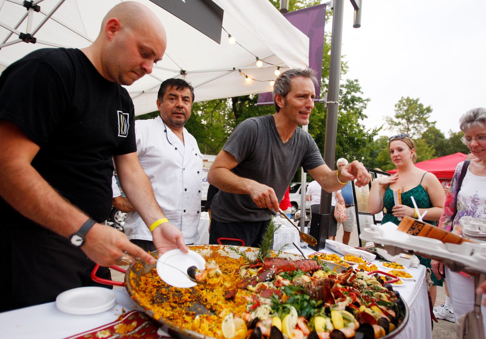 (Lt. to Rt.) SideBar's manager Ben Riddlebarger, chef Alberto Tapia and server Mark Fradl serve up paella during the 23rd annual The Taste festival at Fraze Pavilion in Kettering on Thursday, Sept. 1.