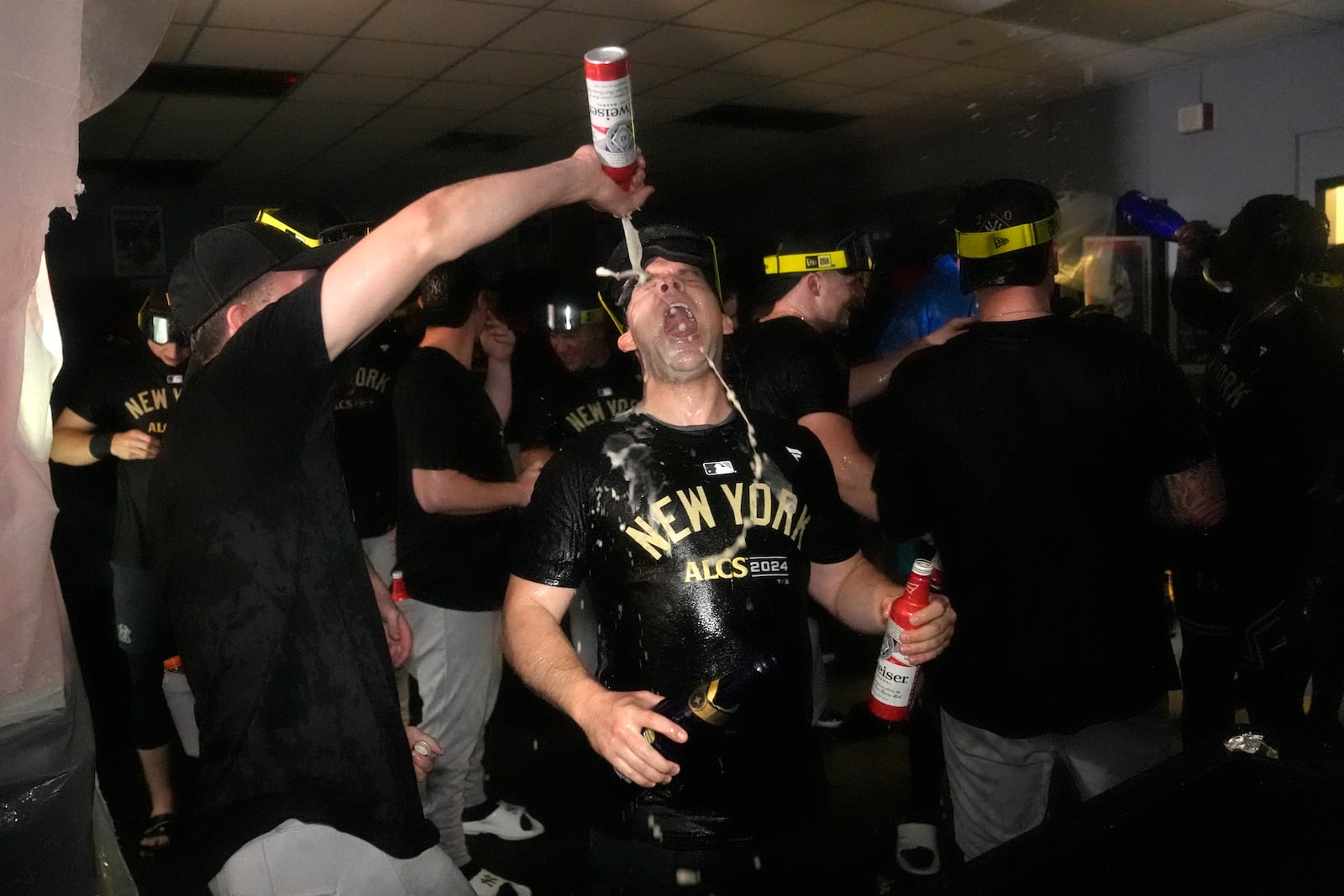 Members of the New York Yankees celebrate in the clubhouse following a 3-1 victory over the Kansas City Royals in Game 4 of an American League Division baseball playoff series Thursday, Oct. 10, 2024, in Kansas City, Mo. (AP Photo/Charlie Riedel)