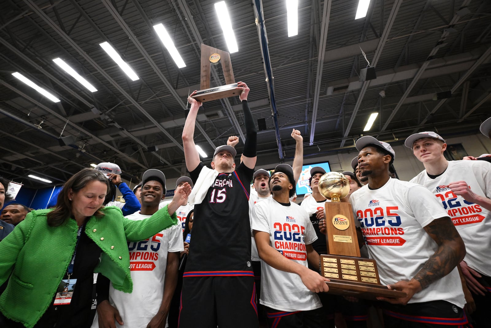 American forward Matt Rogers (15) holds up the league trophy as his teammates celebrate after defeating Navy in an NCAA college basketball game in the championship of the Patriot League tournament, Wednesday, March 12, 2025, in Washington. (AP Photo/Terrance Williams)