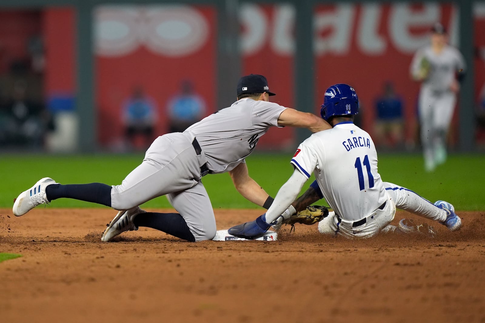 Kansas City Royals' Maikel Garcia, right, is tagged out at second by New York Yankees shortstop Anthony Volpe on a double play during the sixth inning in Game 4 of an American League Division baseball playoff series Thursday, Oct. 10, 2024, in Kansas City, Mo. The Royals' Michael Massey was out at first. (AP Photo/Charlie Riedel)