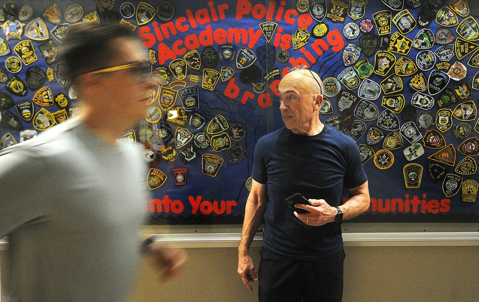 Retired chief and instructor David Miller keeps a stopwatch for cadets running through the halls at Sinclair Community College. MARSHALL GORBY\STAFF