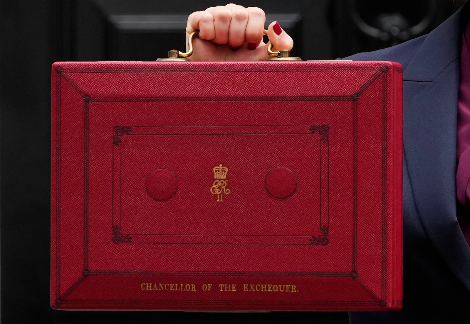 Britain's Chancellor of the Exchequer, Rachel Reeves, holds up the traditional red ministerial box containing her budget speech, as she poses for the media outside No 11 Downing Street, before departing to the House of Commons to deliver the budget in London, Wednesday, Oct. 30, 2024. (AP Photo/Kirsty Wigglesworth)