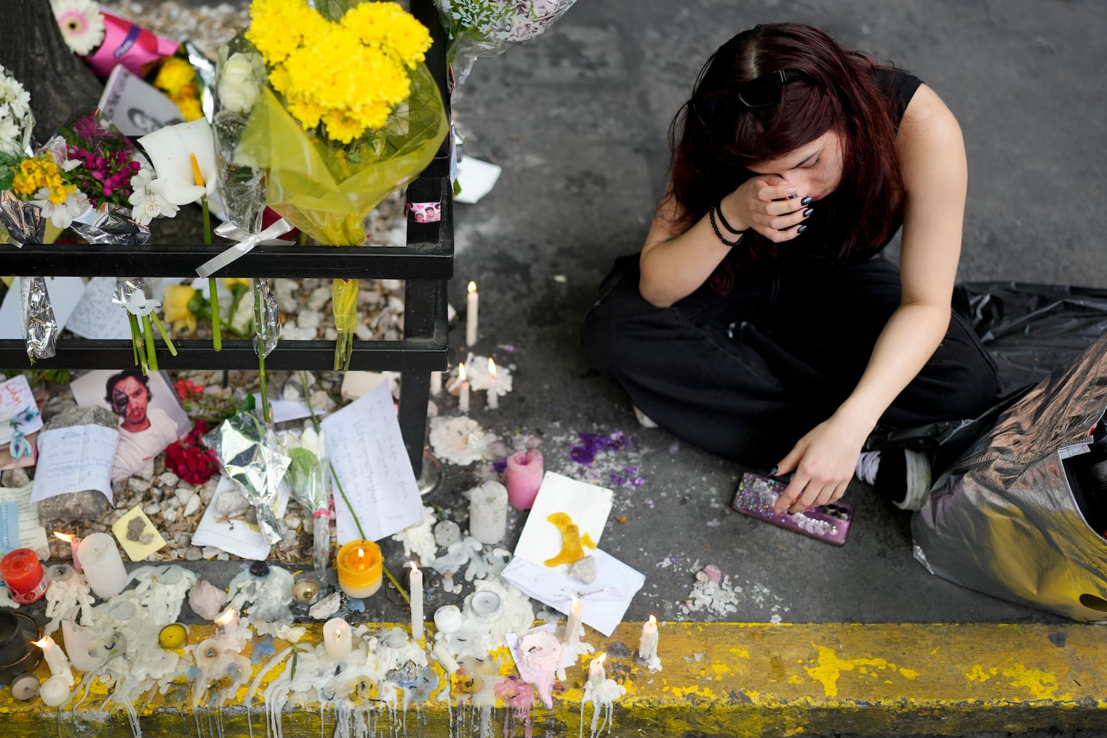 A fan of former One Direction singer Liam Payne cries next to a memorial created by fans outside the hotel where he was found dead after falling from a balcony the previous day in Buenos Aires, Argentina, Thursday, Oct. 17, 2024. (AP Photo/Natacha Pisarenko)