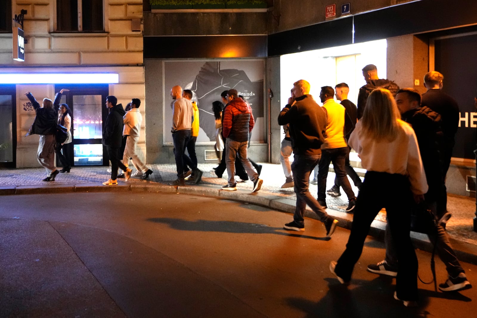 A group of tourists stand in line outside a bar as they attend a pub crawl tour in downtown Prague, Czech Republic, Thursday, Oct. 17, 2024. (AP Photo/Petr David Josek)