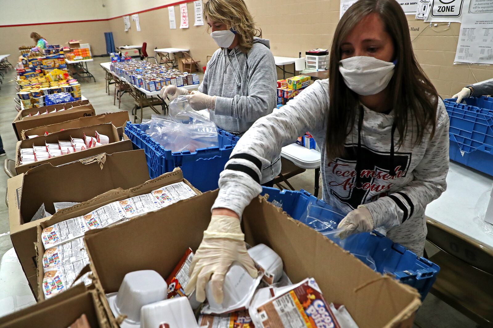 Staff and volunteers at Tecumseh High School, including Natalie Jackson, right, spent Monday afternoon filling food bags for students with food the community donated. BILL LACKEY/STAFF