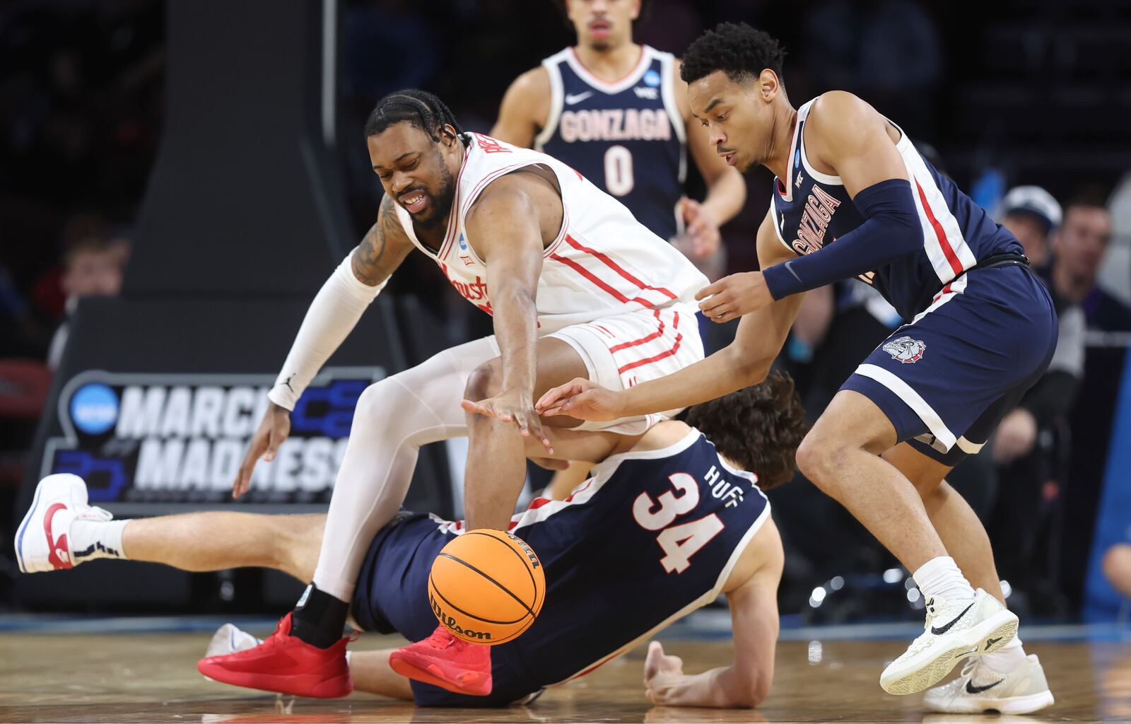 Houston forward J'Wan Roberts, top, falls over Gonzaga forward Braden Huff (34) while Gonzaga guard Nolan Hickman (11) reaches for the ball during the first half in the second round of the NCAA college basketball tournament, Saturday, March 22, 2025, in Wichita, Kan. (AP Photo/Travis Heying)