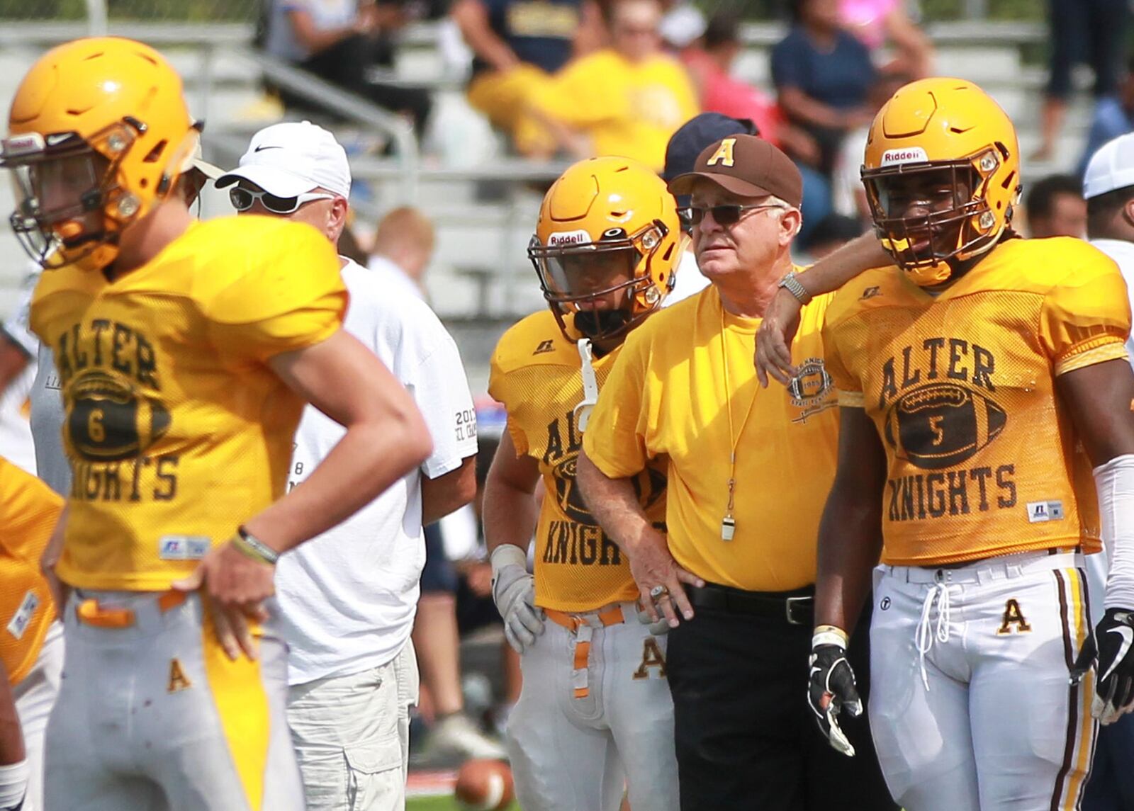 Alter High School football head coach Ed Domsitz (middle) huddles with junior running back Branden McDonald during a scrimmage at Beavercreek on Saturday, Aug. 17, 2019. MARC PENDLETON / STAFF