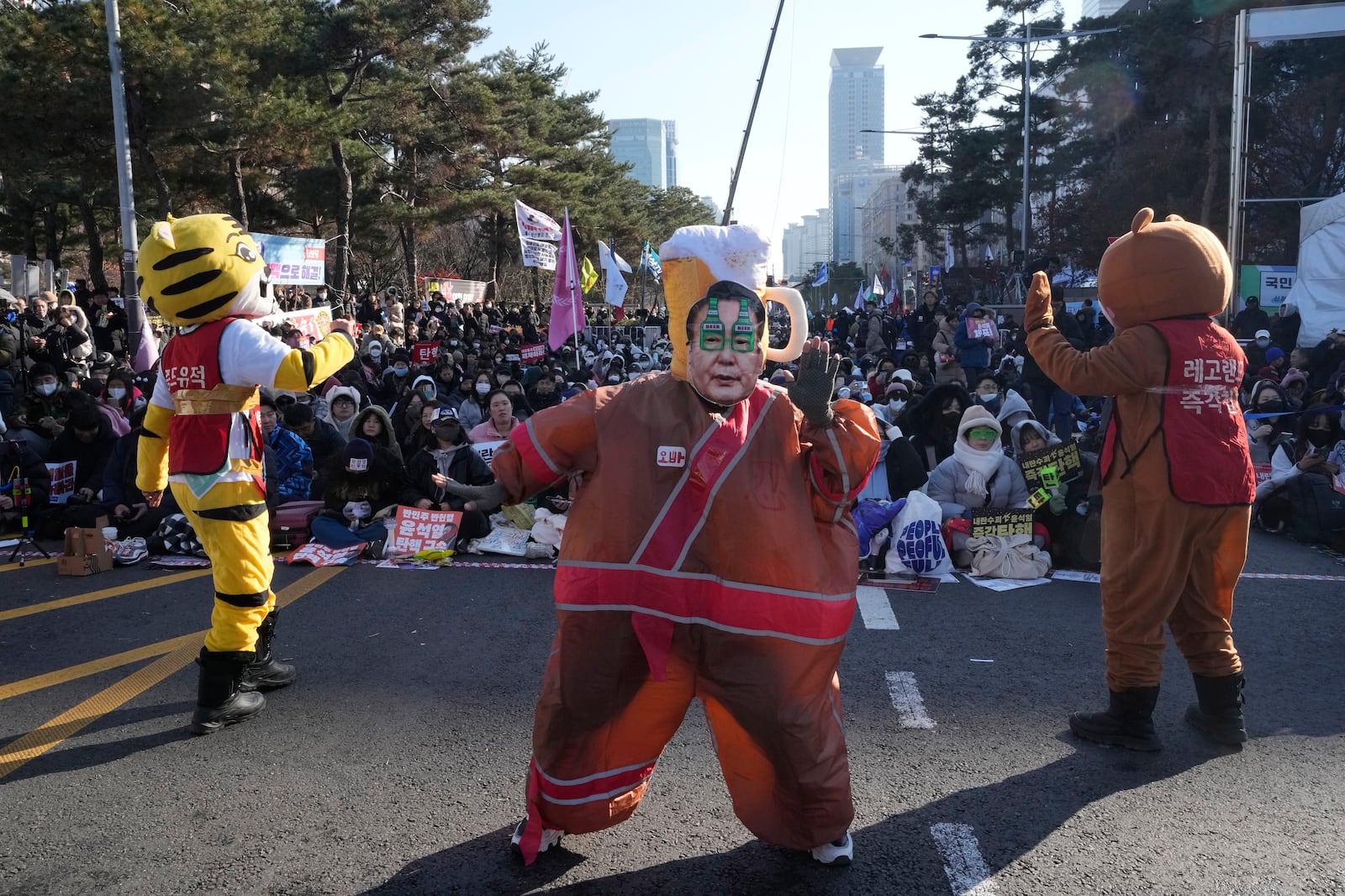 A participant, center, wearing a mask of South Korean President Yoon Suk Yeol performs before a rally to demand his impeachment outside the National Assembly in Seoul, South Korea, Saturday, Dec. 14, 2024. (AP Photo/Ahn Young-joon)